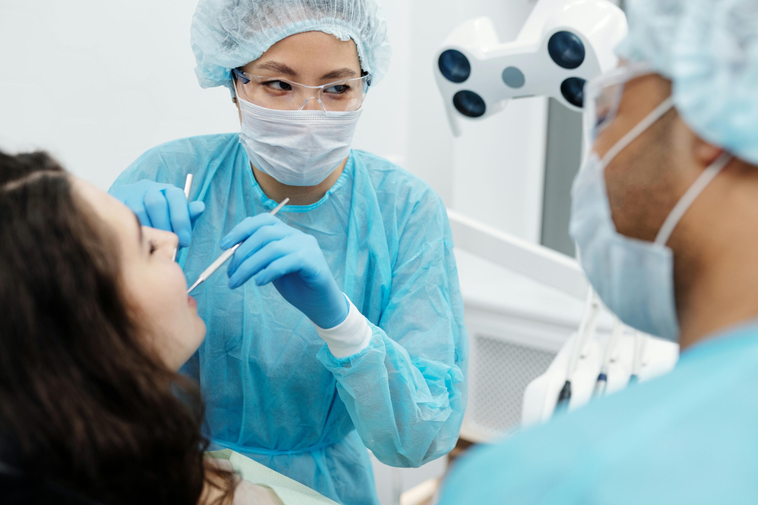 Woman in blue long sleeve scrub suit checking the patient s teeth